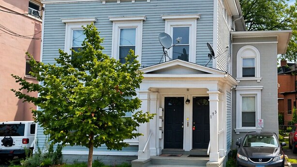 A two-story residential building with a front porch, satellite dishes, and a tree in the front yard. - Free Parking | Walk to Yale & Frank Pepe’s (New Haven)