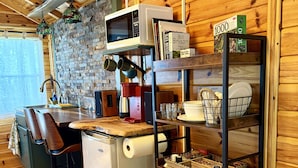 A compact kitchen with a refrigerator, microwave, and a shelf with dishes. - Trailblazer - Cabin w Mtn Views (Black Mountain)