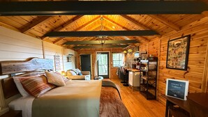 A wooden cabin interior with a bed, kitchenette, and a sign reading 'Welcome to Trailblazer.' - Trailblazer - Cabin w Mtn Views (Black Mountain)