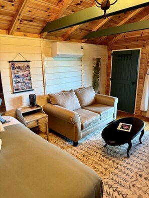 Una habitación acogedora con un sofá, una mesita, una lámpara y una puerta.