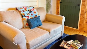 A cozy room with a beige sofa, a black coffee table, and a map on the wall. - Trailblazer - Cabin w Mtn Views (Black Mountain)