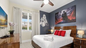 A hotel room with a bed, a desk, a ceiling fan, a window with curtains, and artwork on the walls. - WOW! 6BR Pool Villa w/ Game Room Near Disney (Kissimmee)