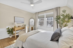 A bedroom with a bed, bedside table, lamp, mirror, window, and a potted plant. - 5BR Toledo Retreat, Hot Tub, Sauna, Sleeps 14 (Toledo)