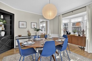 A dining area with a wooden table set for six, blue chairs, a hanging light fixture, and a view of the kitchen through an open doorway. - 5BR Toledo Retreat, Hot Tub, Sauna, Sleeps 14 (Toledo)