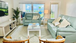 A living room with a sofa, two armchairs, a coffee table, a TV, and a balcony with a view. - Beautiful 4Ba/Br, oceanfront, & ground floor- one of only several on the island! (South Padre Island)