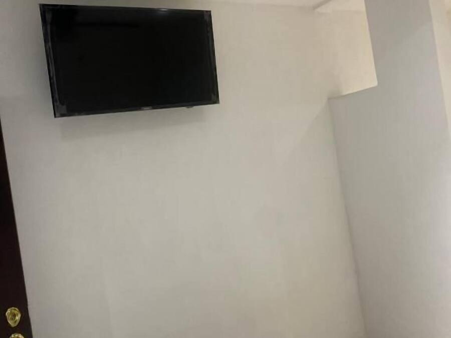A room with a ceiling fan, a mounted TV, and a door with a golden handle.