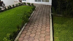 Ein gepflasterter Weg führt zu einem Gebäude mit großen Fenstern und einem grünen Rasen.