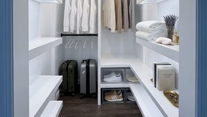 A walk-in closet with white shelving, a hanging rod, and a shoe rack.