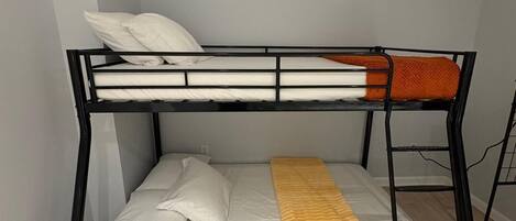 A bunk bed with a ladder, white pillows, and a yellow blanket.