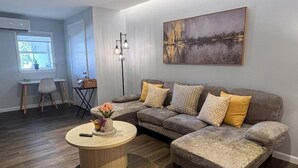 A modern living room with a sectional sofa, a round coffee table, and a painting on the wall.