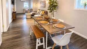 A dining area with a wooden table set for four, a bench, and a potted plant.