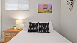 A bedroom with a bed, a nightstand with a lamp, a wall-mounted picture, and a wall-mounted cow skull decoration. - Private Upper Unit Home, Pet Friendly, Min to DT (Arvada)