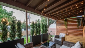 An outdoor patio with wicker furniture, a glass-top table, and a wooden fence with greenery. - Private Upper Unit Home, Pet Friendly, Min to DT (Arvada)
