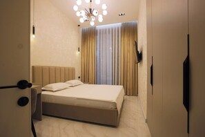 Une chambre d’hôtel avec un lit, un lustre, des rideaux et une armoire.