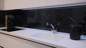 Eine moderne Küche mit weißer Arbeitsplatte, schwarzer Spritzschutzwand und einer Kaffeemaschine.