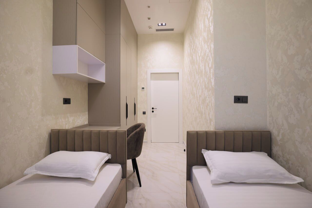Une chambre d’hôtel avec deux lits, une chaise, une armoire et une porte.