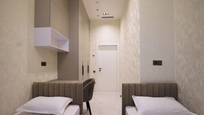 Ein Hotelzimmer mit zwei Betten, einem Sessel, einem Schrank und einer Tür.