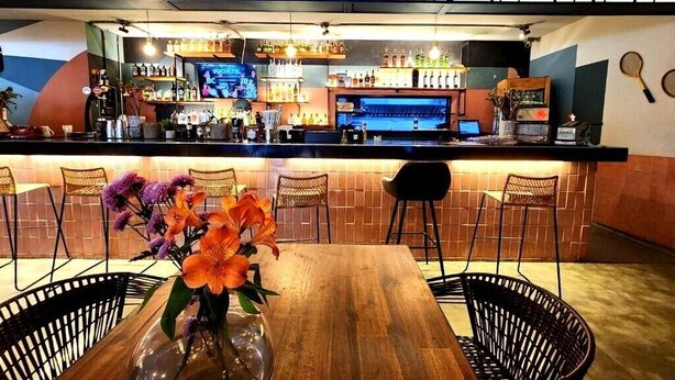 Una zona de bar con una mesa de madera, sillas y un letrero que dice 'For the Good Old Times'.