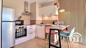 A modern kitchen with stainless steel appliances, wooden accents, and a dining area with bar stools. - Les Elfes - DINARD - City break (DINARD)