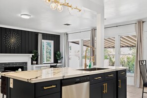 A modern kitchen with a large island, black cabinetry, and a white backsplash. - Stylish 3BR Pasadena Home w/ Yard Near Old Town (Pasadena)