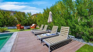 Ein Poolbereich mit Liegestühlen und einem Grill.