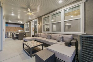 A modern living area with a sectional sofa, a coffee table, and a built-in grill. - Luxe Serenity: EV Charger, Pool, Spa & FirePit (Indio)