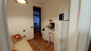 A compact living space with a kitchenette, a dining area, and a sofa with decorative pillows. - Vacation home Annameri (Terrasini)