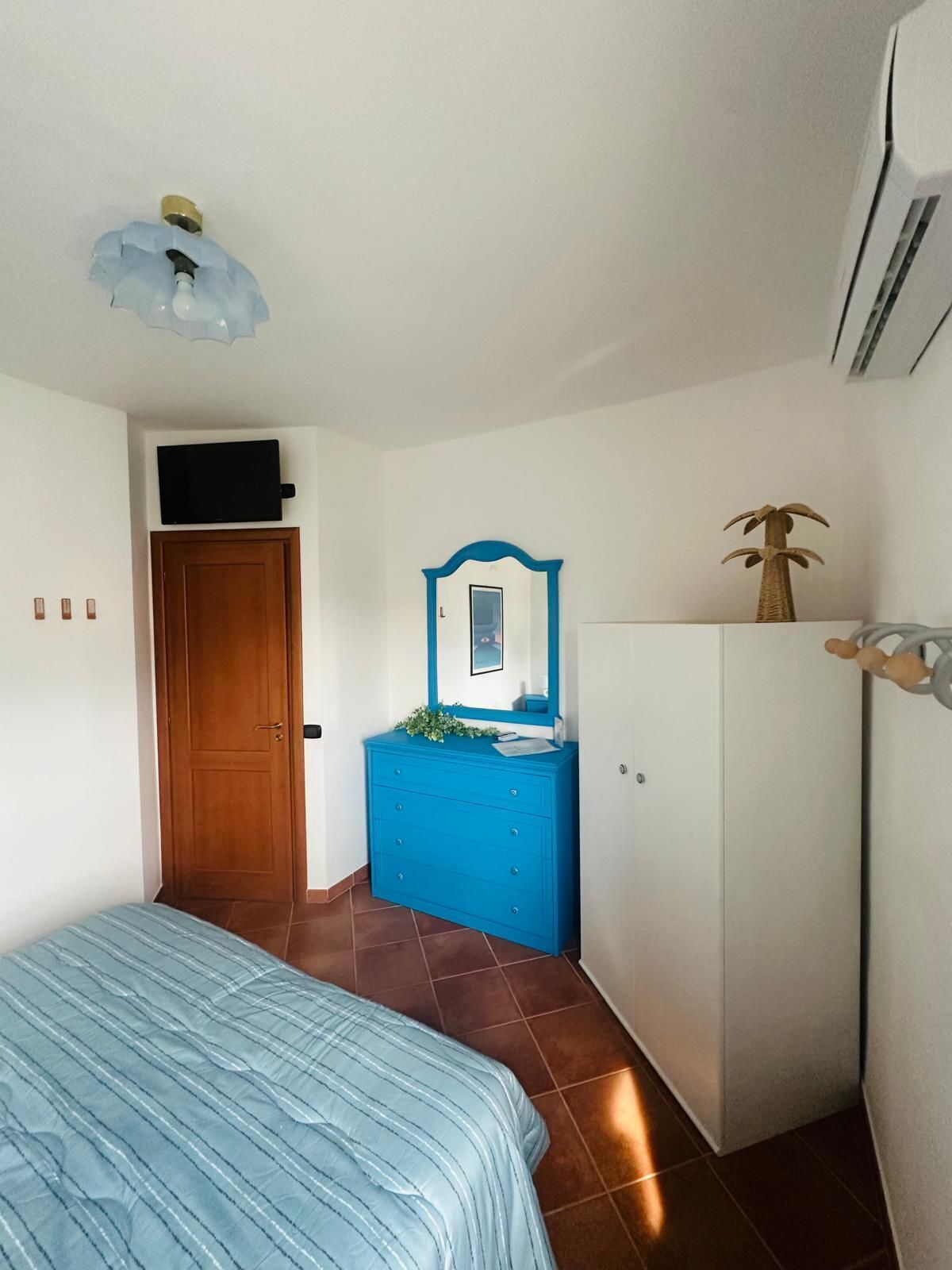 Une chambre à coucher avec un lit, une commode, un miroir et une armoire.