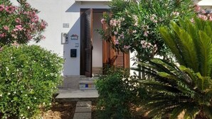 A two-story building with a white exterior, a wooden door, and a small balcony with a railing. - Vacation home Annameri (Terrasini)
