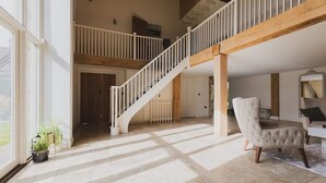 Ein geräumiger Innenraum mit hoher Decke, einer Treppe und einer Sitzecke.