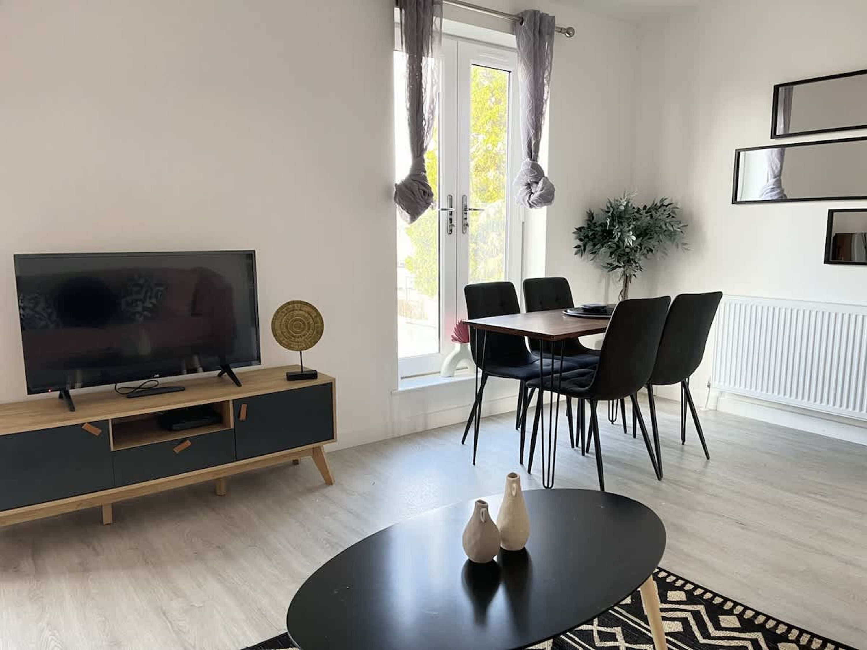 Uma sala de estar moderna com televisão, mesa de jantar, cadeiras e sofá.