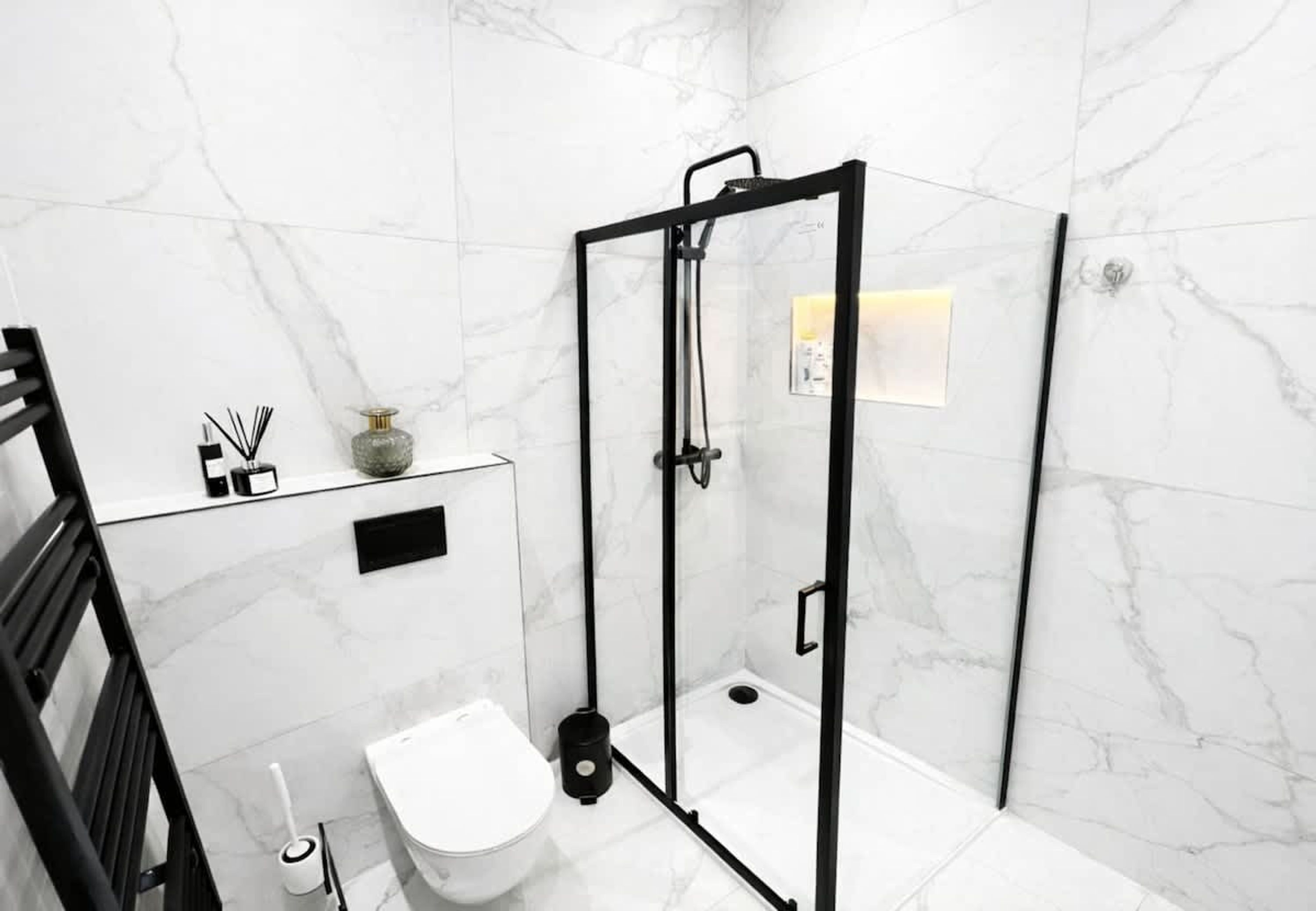 A modern bathroom with a glass-enclosed shower, a toilet, and a sink with a marble countertop.