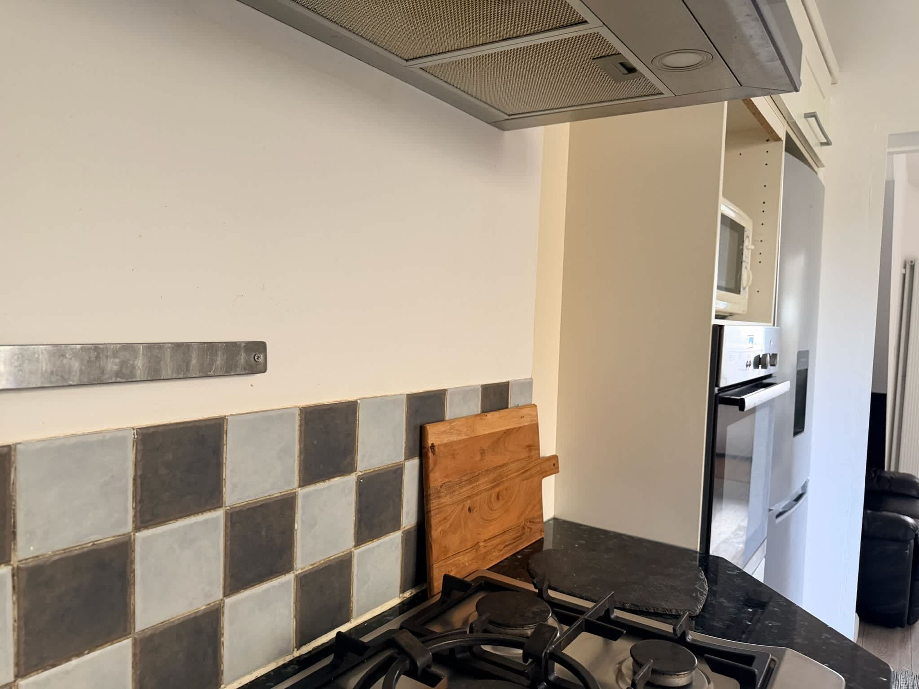 A kitchen with a gas stove, a wooden cabinet, and a microwave.