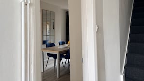 A modern interior with a staircase, a dining area with a table and chairs, and a large mirror.