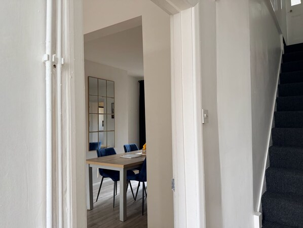 A modern interior with a staircase, a dining area with a table and chairs, and a large mirror. - Riverside Cambridge House - Garden Log Burner Waterfront View (Cambridge)