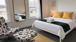 A hotel room with a bed, a chair, a mirror, and a window.