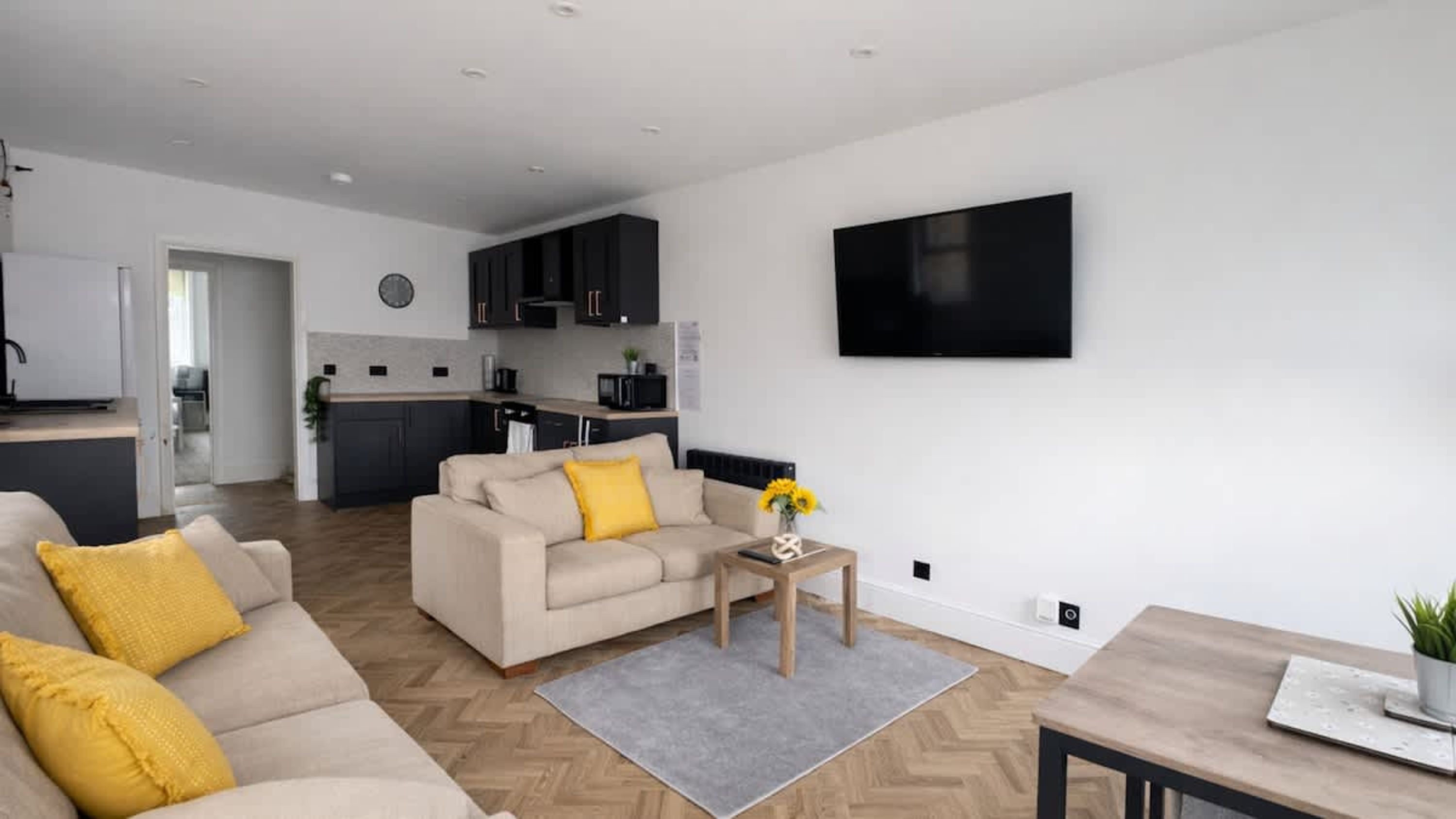 A modern living room with a sofa, coffee table, and a TV mounted on the wall.