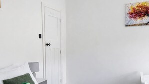 A hotel room with a bed, pillows, a blanket, a towel, a desk, a chair, a lamp, and a painting on the wall. - Ramsey 2BR Apart NR A14 A1 Long Stay Discount (Huntingdon)