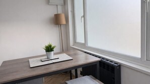 A room with a wooden table, a potted plant, a lamp, and a radiator. - Ramsey 2BR Apart NR A14 A1 Long Stay Discount (Huntingdon)