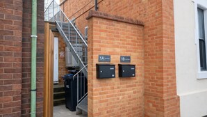 A brick building with a metal staircase, two mailboxes, and a door with a no-smoking sign. - Ramsey 2BR Apart NR A14 A1 Long Stay Discount (Huntingdon)