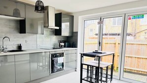 A modern kitchen with stainless steel appliances, a built-in oven, and a dining area with a table and chairs. - Tanzanite Ground Floor 2BR Apart Pet Friendly (Cambridge)