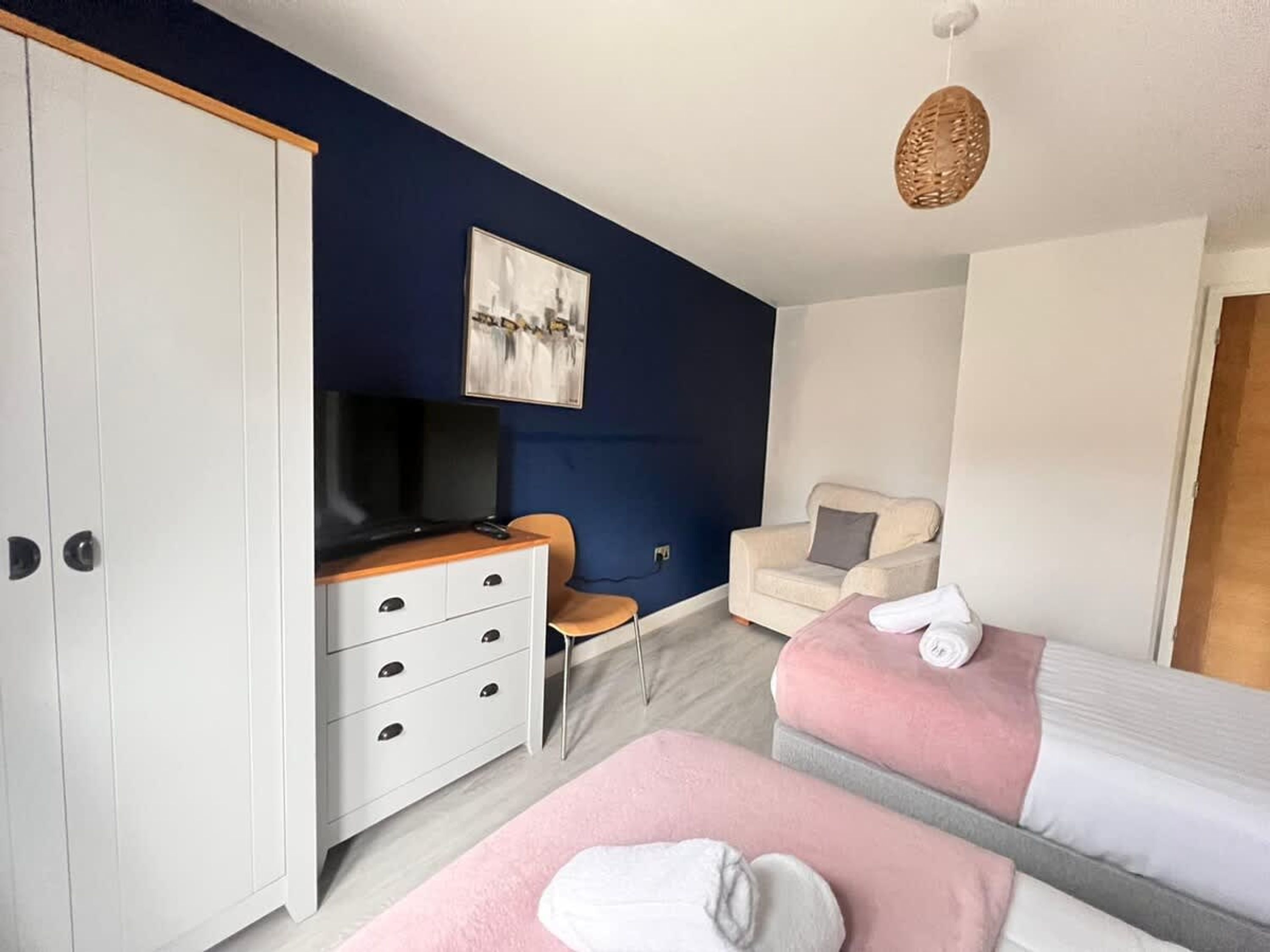 Un dormitorio con un armario, televisor, una silla y dos camas.