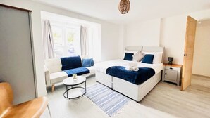 A modern hotel room with a bed, a sofa, a small table, and a nightstand. - Tanzanite Ground Floor 2BR Apart Pet Friendly (Cambridge)