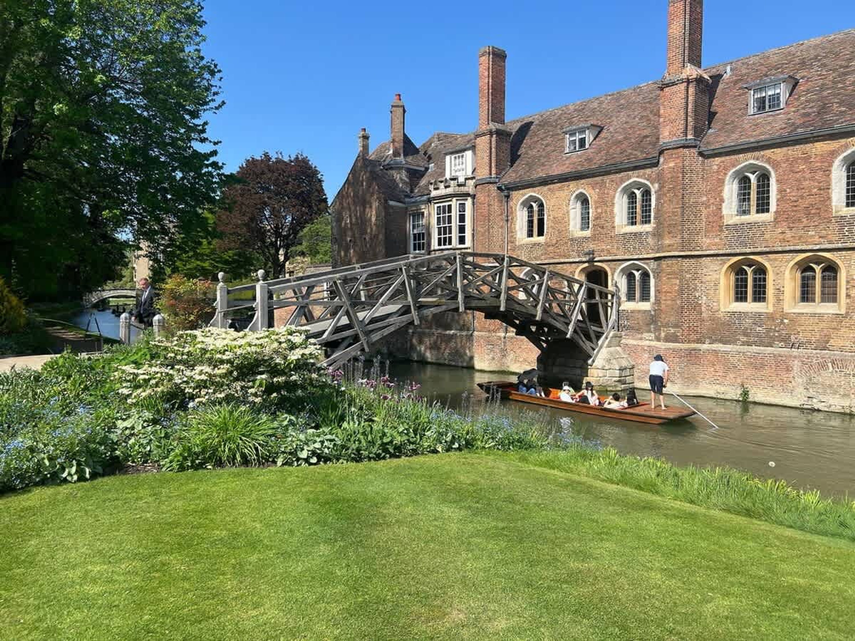 Un edificio storico con un ponte sopra un canale, immerso nel verde.