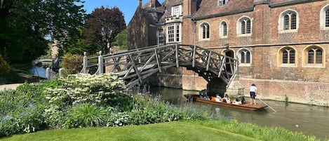 A historic building with a bridge over a canal, surrounded by greenery.