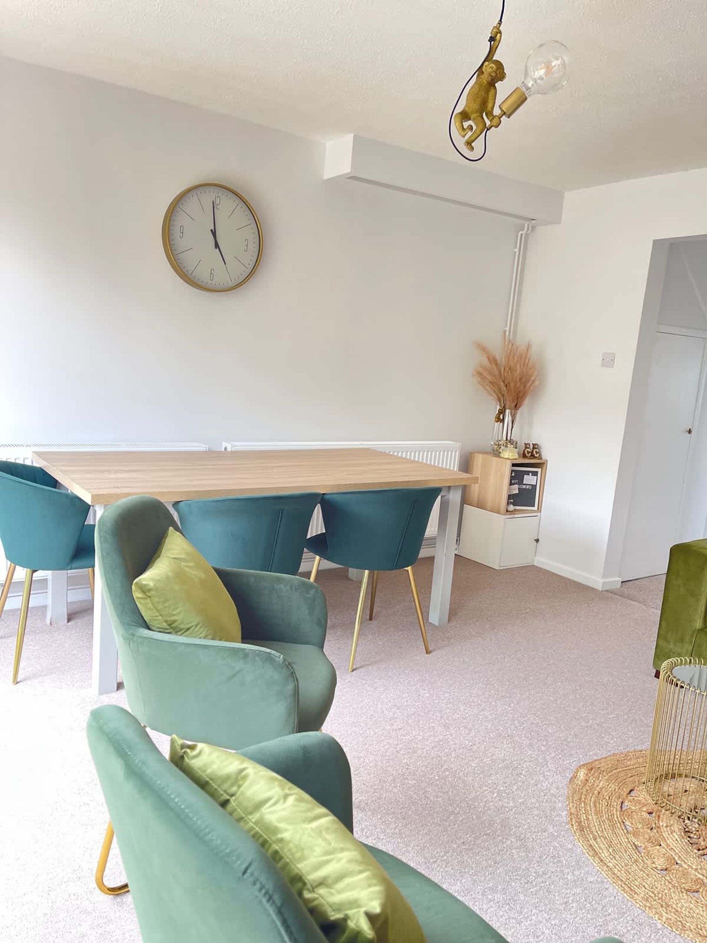 Un comedor con una mesa y sillas de madera, un reloj de pared y una lámpara colgante.