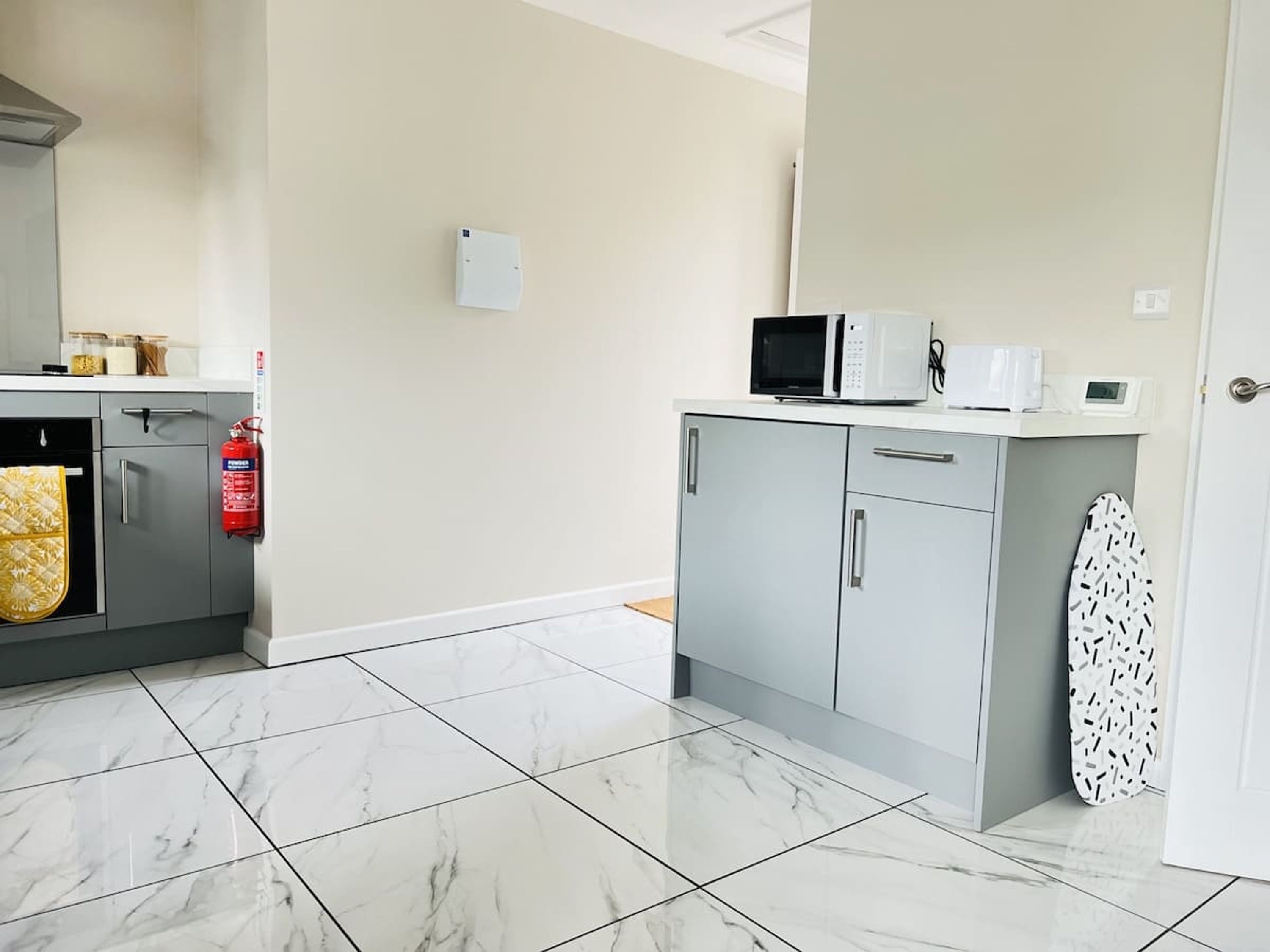 A kitchen with a microwave, toaster, and a fire extinguisher.