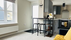 Una cocina moderna con armarios grises, encimera negra y una ventana con persianas.