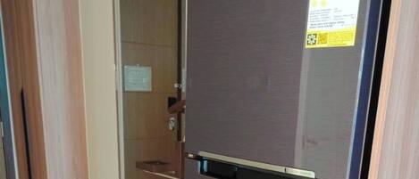 A Samsung refrigerator in a kitchen with wooden cabinets and a metal drying rack.
