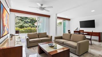 Una sala de estar moderna con dos sofás, una mesa de centro, un televisor y un ventilador de techo.
